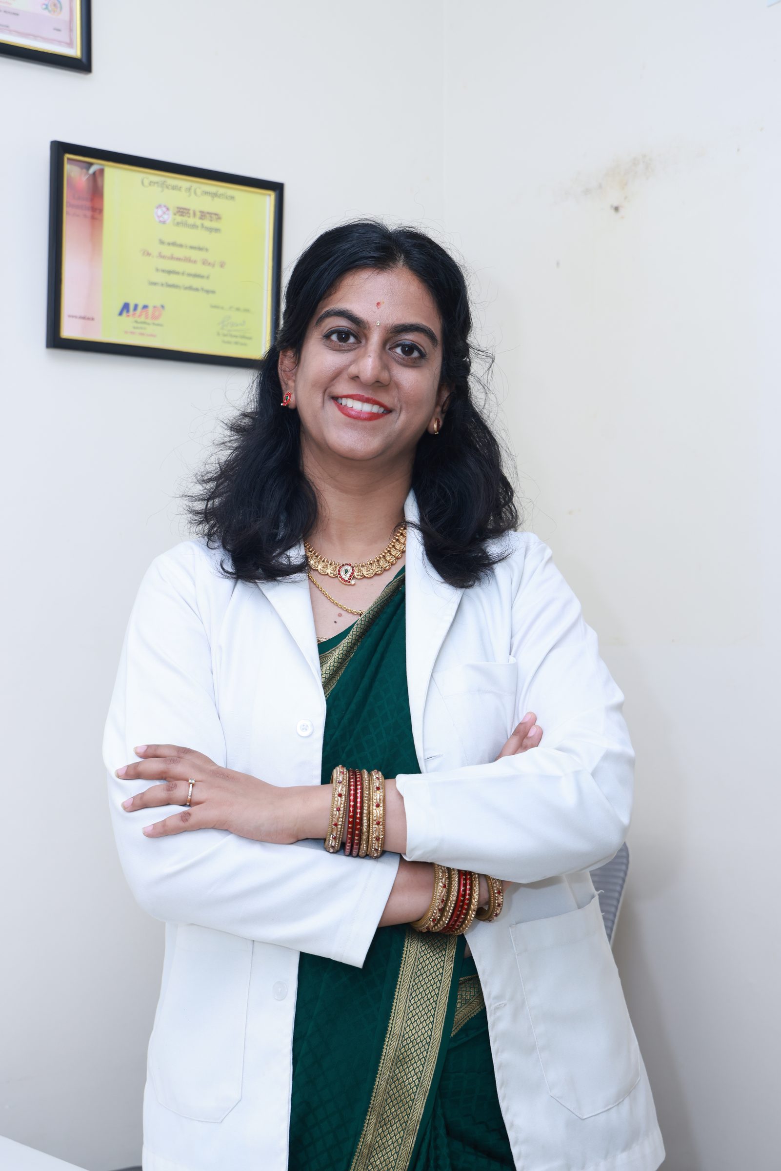 Dr. Sushmitha in her white coat, standing with arms crossed