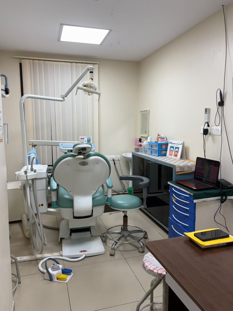 A dental treatment room with a treatment chair, overhead dental light and clinical workspace